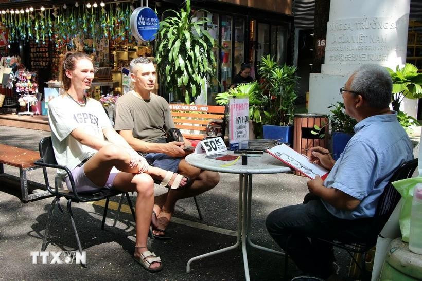 Foreign tourists enjoy a painting service on Nguyen Van Binh book street in Ho Chi Minh City. (Photo: VNA)