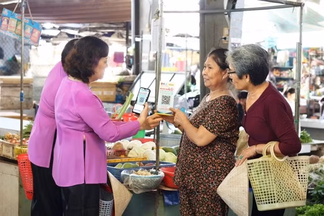 Vendors guide customers in making cashless payments in Ho Chi Minh City. (Photo: phunuonline.com.vn)