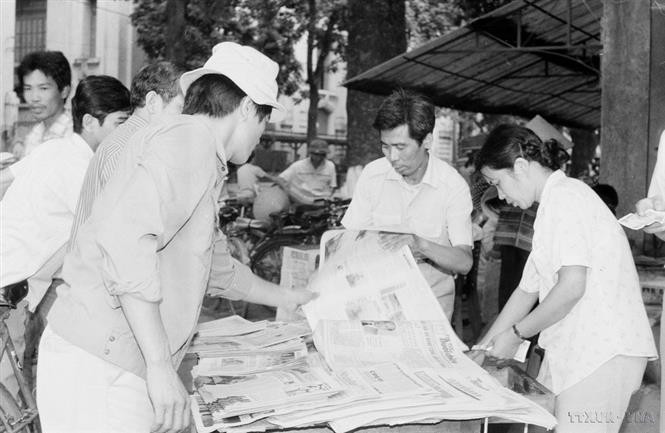 Residents of the capital buy and read the "Tin tuc buoi chieu" (afternoon news) newspaper, published by the Vietnam News Agency (VNA), to stay updated on the closing session of the 7th National Congress of the Communist Party of Vietnam (July 17, 1991). (Photo: VNA)