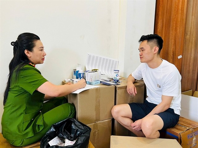 Pham Ngoc Tien is questioned by a police officer. (Photo: daibieunhandan.vn)