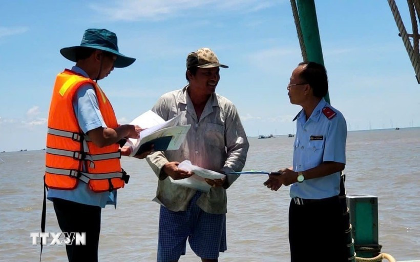Officers check a fisherman's compliance with regulations on combating IUU fishing. (Photo: VNA)