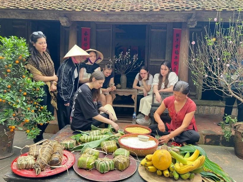 Foreign tourists wrap 'banh chung' as part of “Tet Lang Viet” programme. (Photo: VNA)