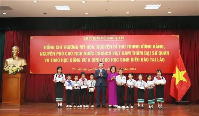 Chairwoman of the Vu A Dinh Fund Truong My Hoa and Vietnamese Ambassador to Laos Nguyen Minh Tam present scholarships to overseas Vietnamese students. (Photo: VNA)