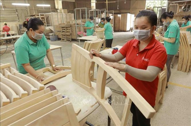 Workers make wooden furniture for export to the US, UK and EU markets at the factory of the Thiet Dan Two-Member Company Limited. (Photo: VNA)