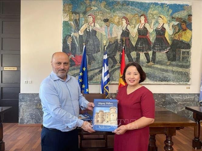 Deputy Mayor of Rhodes in charge of economy, finance, and cultural heritage Chalkias Konstantinos (L) presents a book to Vietnamese Ambassador to Greece Pham Thi Thu Huong. (Photo: Published by VNA)