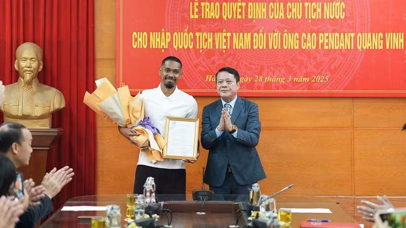 A representative of the Hanoi Department of Justice hands over the decision to footballer Cao Pendant Quang Vinh (left). (Photo: nhandan.vn)