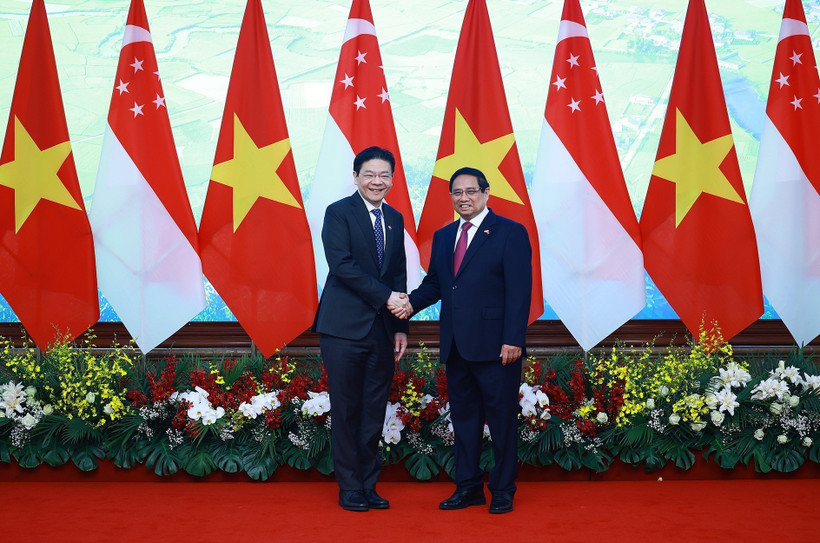 Prime Minister Pham Minh Chinh (R) shakes hands with his Sngaporean counterpart Lawrence Wong in Hanoi on March 26. (Photo: VNA)