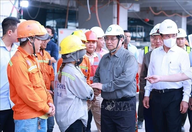 Prime Minister Pham Minh Chinh (second from the right) extends New Year greetings to workers at the construction site of the Terminal 3 project at Tan Son Nhat International Airport in Ho Chi Minh City. (Photo: VNA)