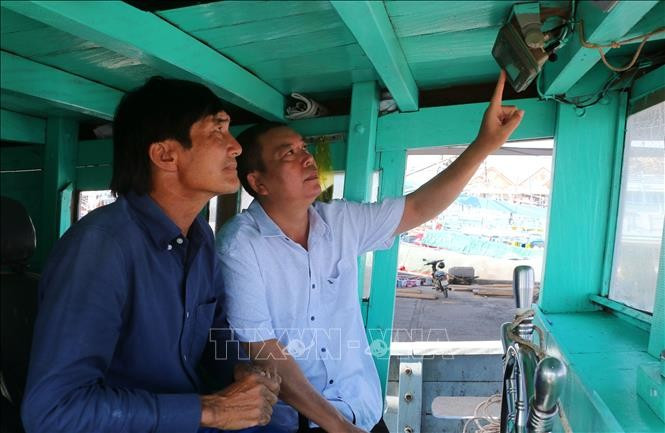 A representative of the Tran De fishing port management board inspects a vessel monitoring device on a fishing boat docked at the port. (Photo: VNA)