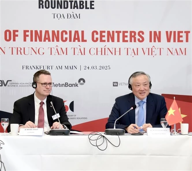 Permanent Deputy Prime Minister Nguyen Hoa Binh (R) speaks at the roundtable on the building of financial centres in Vietnam in Germany. (Photo: VNA)