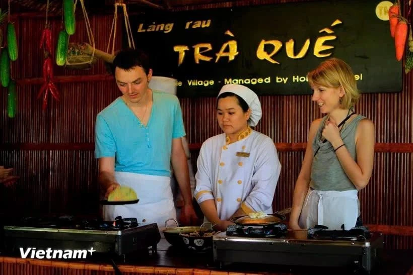 Foreign tourists experience making "banh xeo" in Tra Que vegetable village, Hoi An city, Quang Nam province (Photo: VNA)