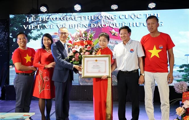 Vietnamese Ambassador to Germany Vu Quang Minh presents a certificate of merit and flowers to Bui Thi Thu Minh, head of the Vietnamese Liaison Committee in Europe "For Vietnam's Seas and Islands", President of the Truong Sa Club in Germany. (Photo: VNA) 
