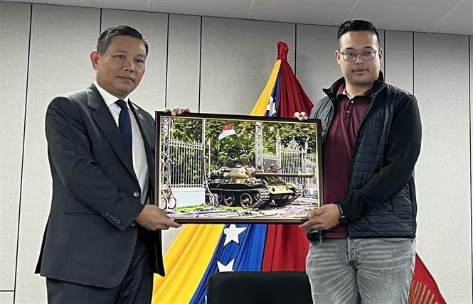 Vietnamese Ambassador to Venezuela Vu Trung My (left) presents a photo of the April 30 victory to a representative of the Antonio Jose de Sucre International Youth Leadership Training School. (Photo courtesy of the Vietnamese Embassy in Venezuela)