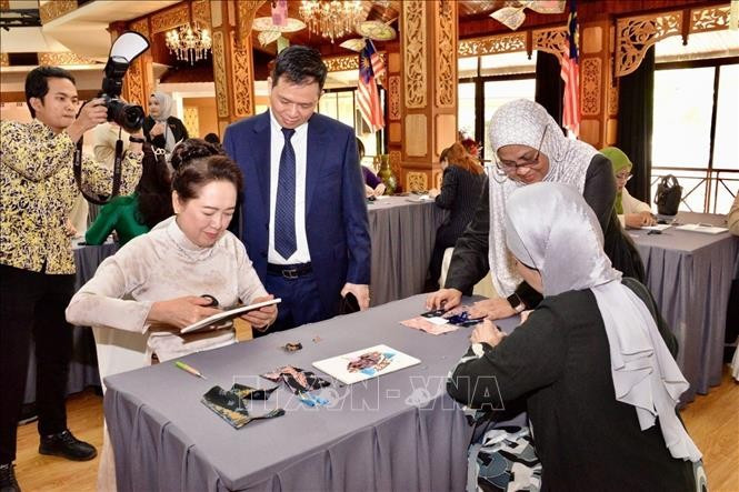 National Assembly (NA) Chairman Tran Thanh Man’s spouse, Nguyen Thi Thanh Nga (left) and Datin Dr. Rozana binti Kamal, spouse of the Speaker of the Malaysian House of Representatives, experience traditional fabric printing and painting. (Photo: VNA).