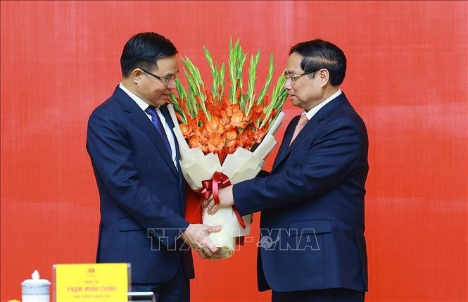 PM Pham Minh Chinh presents congratulatory flowers to Acting Minister of Industry and Trade Le Manh Hung. (Photo: VNA)