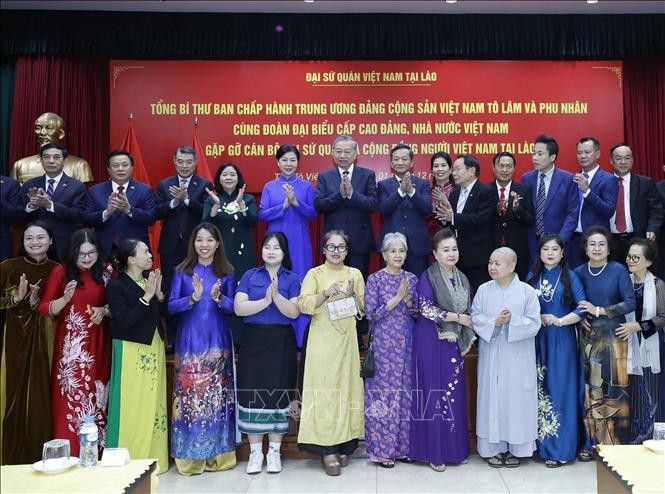 Party General Secretary To Lam and his spouse, staff of the Vietnamese Embassy and representatives of the Vietnamese community in a group photo at their meeting in Vientiane on December 1 evening. (Photo: VNA)