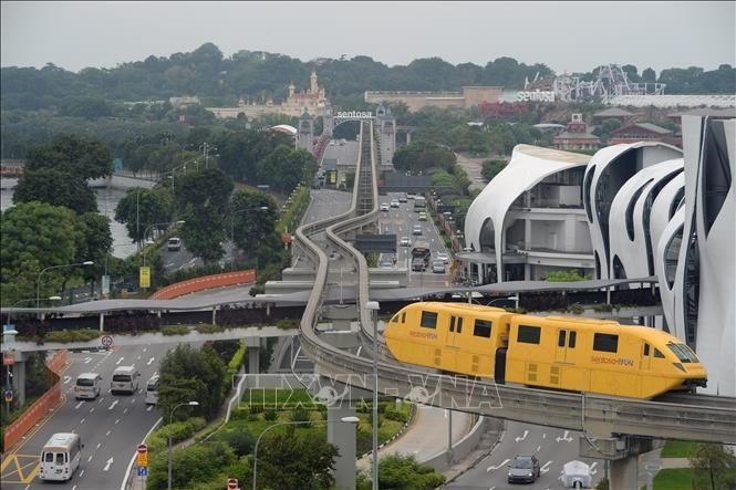 Public transport vehicles and private cars travel on a street in Singapore (Photo: AFP/VNA)