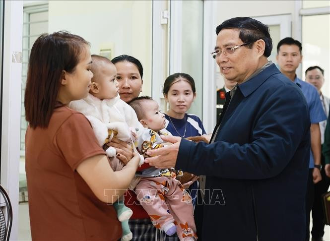 Prime Minister Pham Minh Chinh talks to people receiving medical services at the Yen Khuong health station in Thanh Hoa province on November 9. (Photo: VNA)
