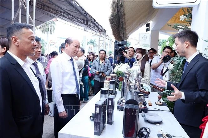 Delegates visit a booth displaying coffee making machinery and equipment at the fair. (Photo: VNA)