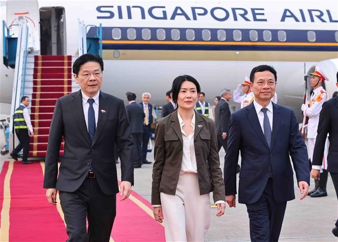 Prime Minister of Singapore Lawrence Wong (L) and his spouse (C) arrive in Hanoi on March 25 afternoon, beginning a two-day official visit to Vietnam. (Photo: VNA)