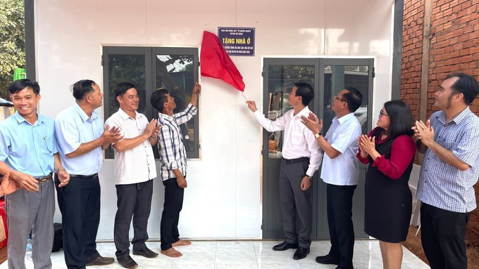 Secretary of the Bu Dang district Party Committee and Head of the Steering Committee for Eliminating Dilapidated Housing, Vu Luong (fourth from right), performs the ribbon-cutting ceremony to hand over a new house to a disadvantaged household. (Photo: VNA) 