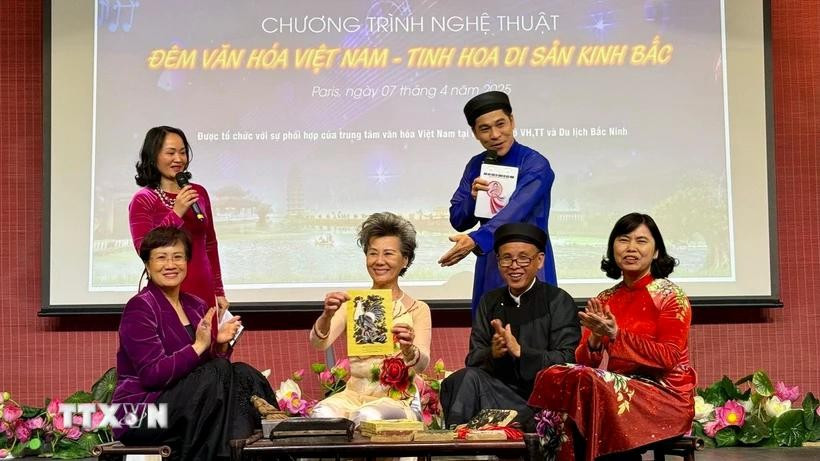 Introducing and demonstrating Dong Ho painting to the audience. (Photo: VNA)