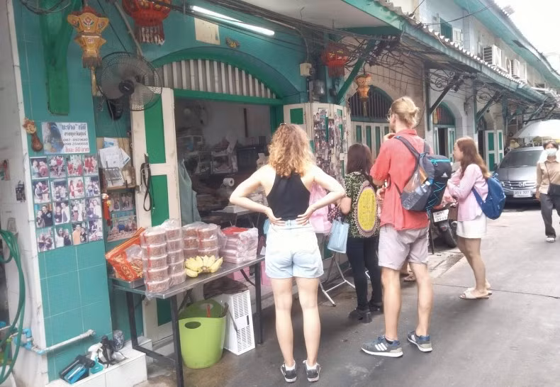 Two foreign tourists buy curry puffs at the popular Khun Phu shop in the Talat Noi community in Bangkok on Monday. (Photo: bangkokpost.com) 