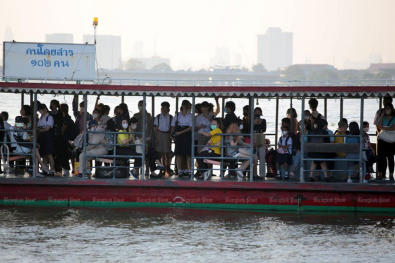 Thai students and other passengers, many wearing face masks, ride a boat along the Chao Phraya River. (Photo: Bangkok Post) 