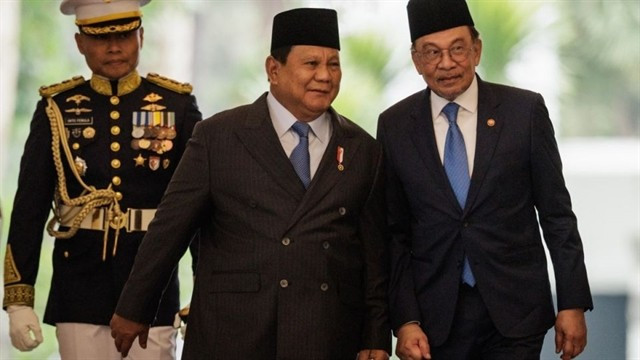 Malaysia's Prime Minister Anwar Ibrahim (right) and Indonesia’s President Prabowo Subianto (centre) walk together ahead of their bilateral meeting at the Presidential Palace in Jakarta on July 29. (Photo: AFP/VNA) 