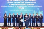 Party General Secretary To Lam and officials witness the exchange of cooperation documents between Vietnamese and Singaporean firms at a business roundtable in the city state on March 13. (Photo: VNA)