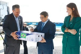 PM Pham Minh Chinh (C) signs on a pack of beef exported to Vietnam. (Photo: VNA)
