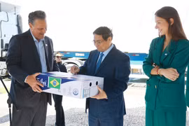 PM Pham Minh Chinh (C) signs on a pack of beef exported to Vietnam. (Photo: VNA)