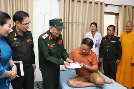 Major General Vo Van Chot, head of Nghe An province’s liaison board for former Vietnamese volunteer soldiers and military experts in Laos, presents a gift to a patient at Military Central Hospital 103 of Laos. (Photo: VNA)