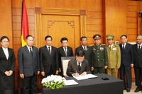 Party General Secretary and President of Laos Thongloun Sisoulith writes in the condolence book. (Photo: VNA)