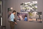 A visitor admires photos by Nicolas Cornet at the “Hanoi Oi” exhibition – an event held in conjunction with the launch of the book of the same name. (Photo: VietnamPlus)