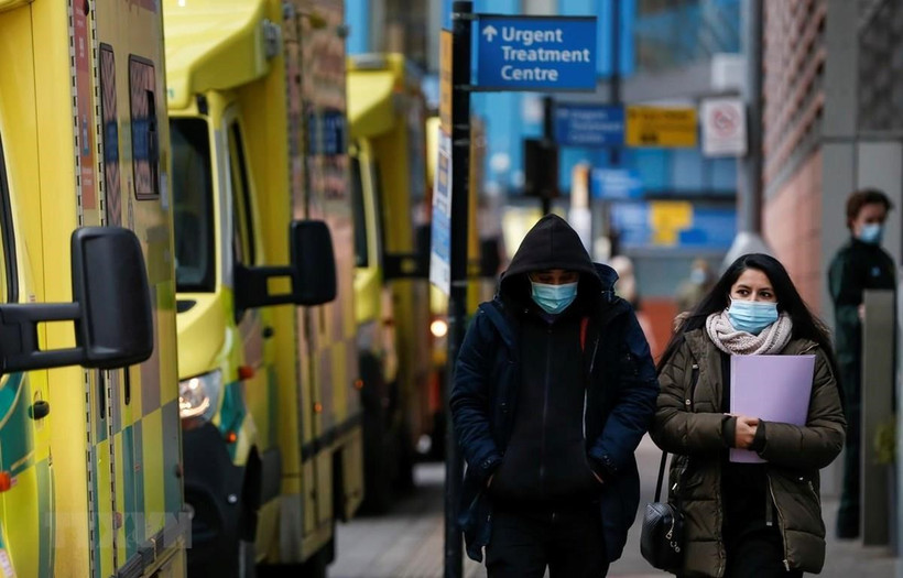 People wearing face masks walk in London, the United Kingdom, on January 26, 2021. (Photo: Xinhua/VNA)