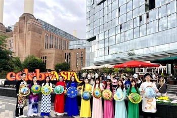 The Vietnamese delegation parades in traditional ao dai and conical hats along the streets of London. (Photo published by VNA) 