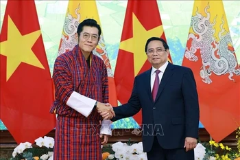 Prime Minister Pham Minh Chinh (R) welcomes King of Bhutan Jigme Khesar Namgyel Wangchuck in Hanoi on August 19. (Photo: VNA)