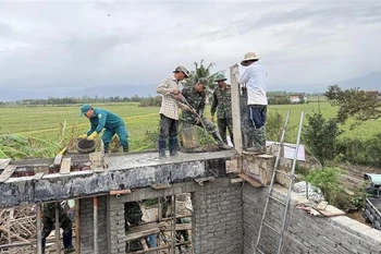 Soldiers and trainees from the Military School of Military Region 5 are pouring concrete pillars and constructing the second floor according to the design to provide shelter for residents during floods. (Photo: VNA)