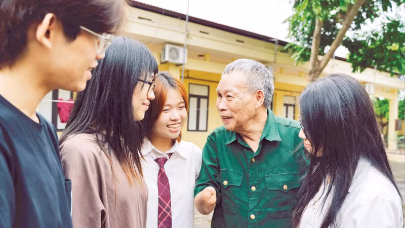 Members of the "Stories in Peacetime" project listen to veteran Do Dang Khuay sharing his experience as they visit him at the Thuan Thanh Nursing Centre for War Invalids in Bac Ninh province. (Photo: nhandan.vn) 