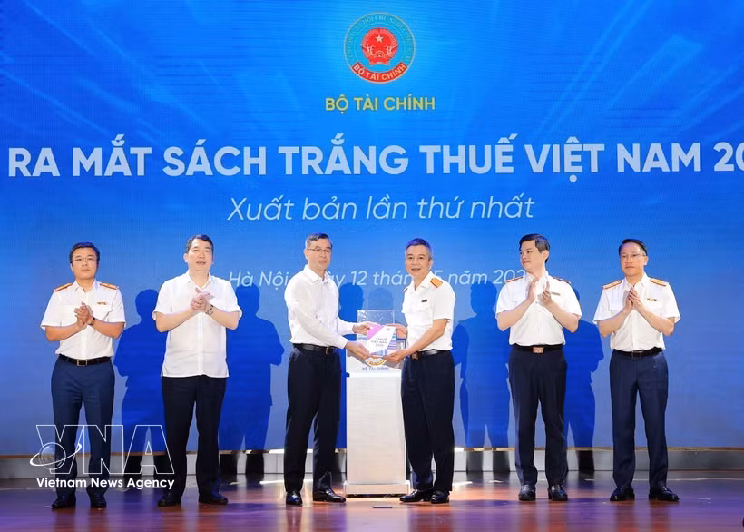 Minister of Finance Ngo Van Tuan (third from left) presents the White Book on Vietnam Taxation 2026 to Director the Tax Department Mai Xuan Thanh at the launch in Hanoi on May 12. (Photo: VNA) 