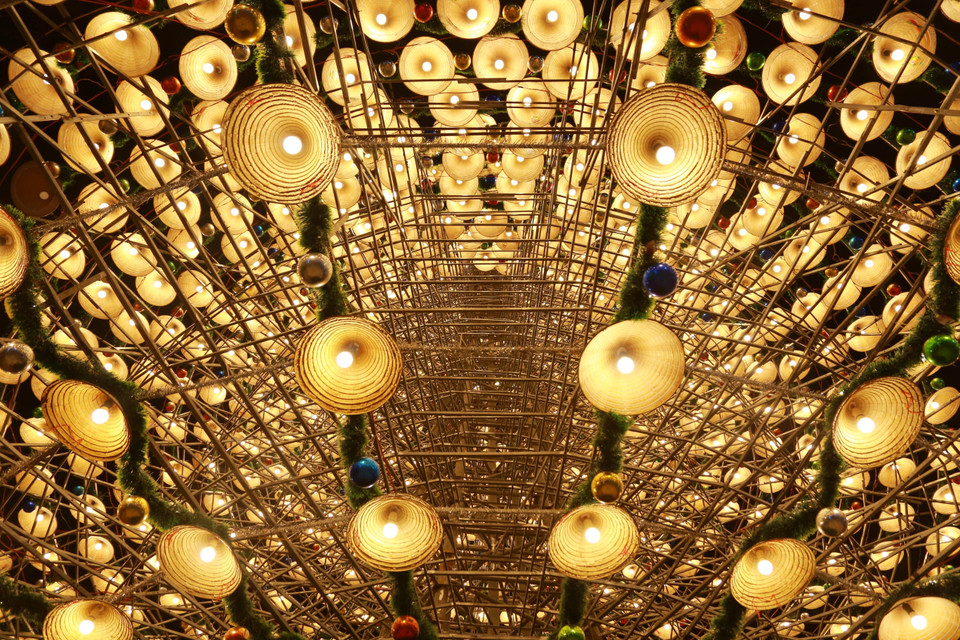 The tree is decorated with layers of conical hats, light bulbs, tinsel, and baubles, creating a mysterious and captivating beauty. (Photo: VNA)