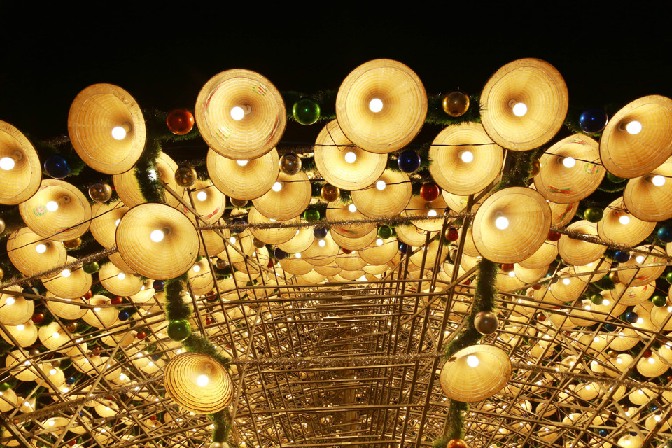 The tree is decorated with layers of conical hats, light bulbs, tinsel, and baubles, creating a mysterious and captivating beauty. (Photo: VNA)