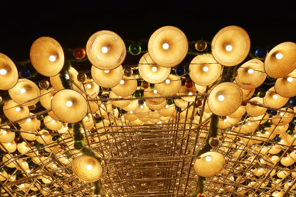 The tree is decorated with layers of conical hats, light bulbs, tinsel, and baubles, creating a mysterious and captivating beauty. (Photo: VNA)