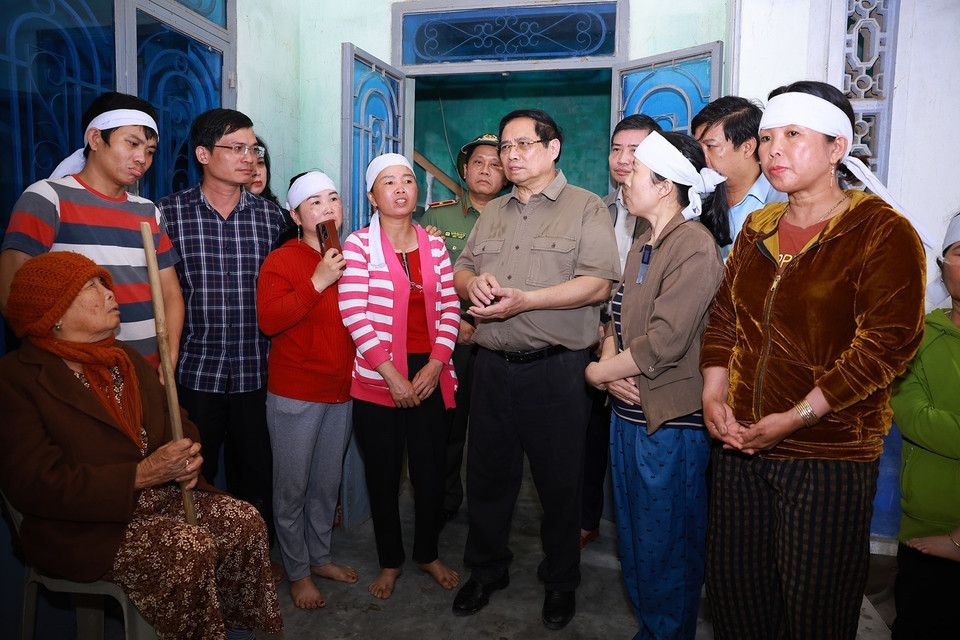 Prime Minister Pham Minh Chinh visits and encourages a family severely affected by the floods in Phu Huu village, Hoa Thinh commune. (Photo: VNA)