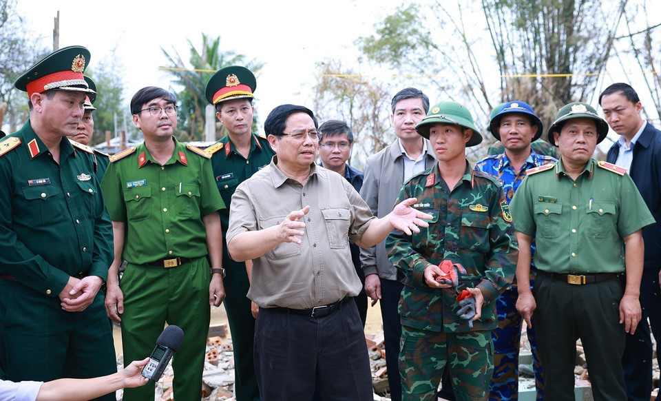 Prime Minister Pham Minh Chinh visits the flooded area of Phu Huu village, Hoa Thinh commune, and reviews a report on plans to build flood-resistant houses for residents in the affected areas. (Photo: VNA)