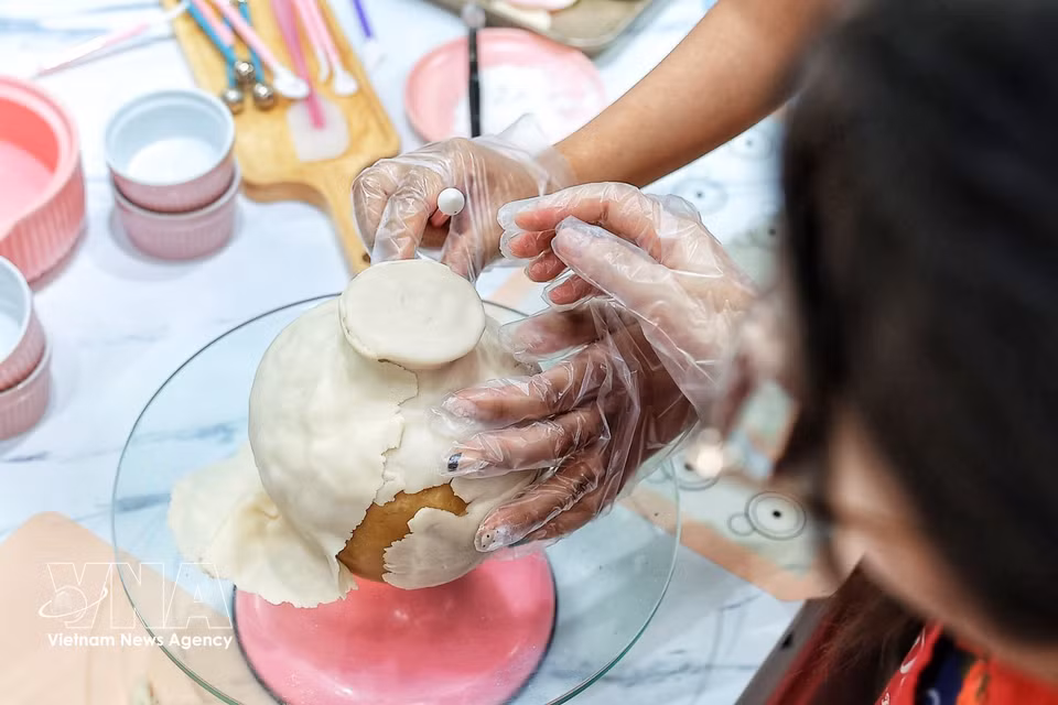 The artisan carefully smooths and shapes the outer layer of mooncake dough to form the vase before decorating it with handcrafted tò he flowers and stems. (Photo: Pham Tuan Anh/VNA)