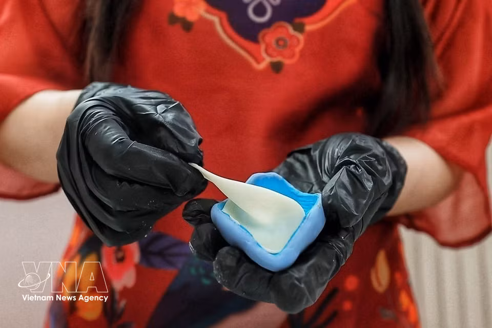 Each petal is moulded from tò he dough, pressed thin and carefully shaped by hand before being assembled into a flower. The technique allows the artisan to create delicate curves and natural-looking details. (Photo: Pham Tuan Anh/VNA)