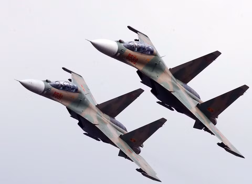The Su-30MK2s tilt their wings as they are flying over the airport grandstand (Photo: VNA)