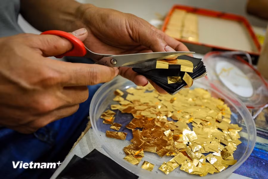 The processes of cutting the gold leaves and transferring them must be carried out in a closed room without the use of fans. This is essential because the gold leaves become extremely thin after being hammered, and even a light breeze can cause them to fly away. (Photo: Vietnam+)